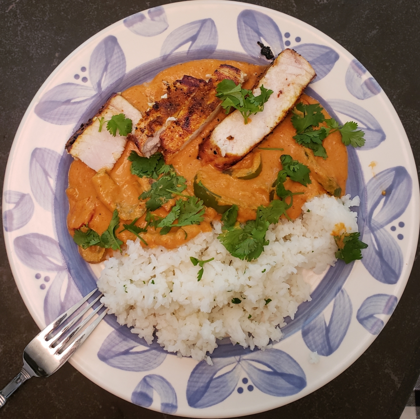 Top-down view of a plate with cuts of swordfish on a bed of orange curry and rice