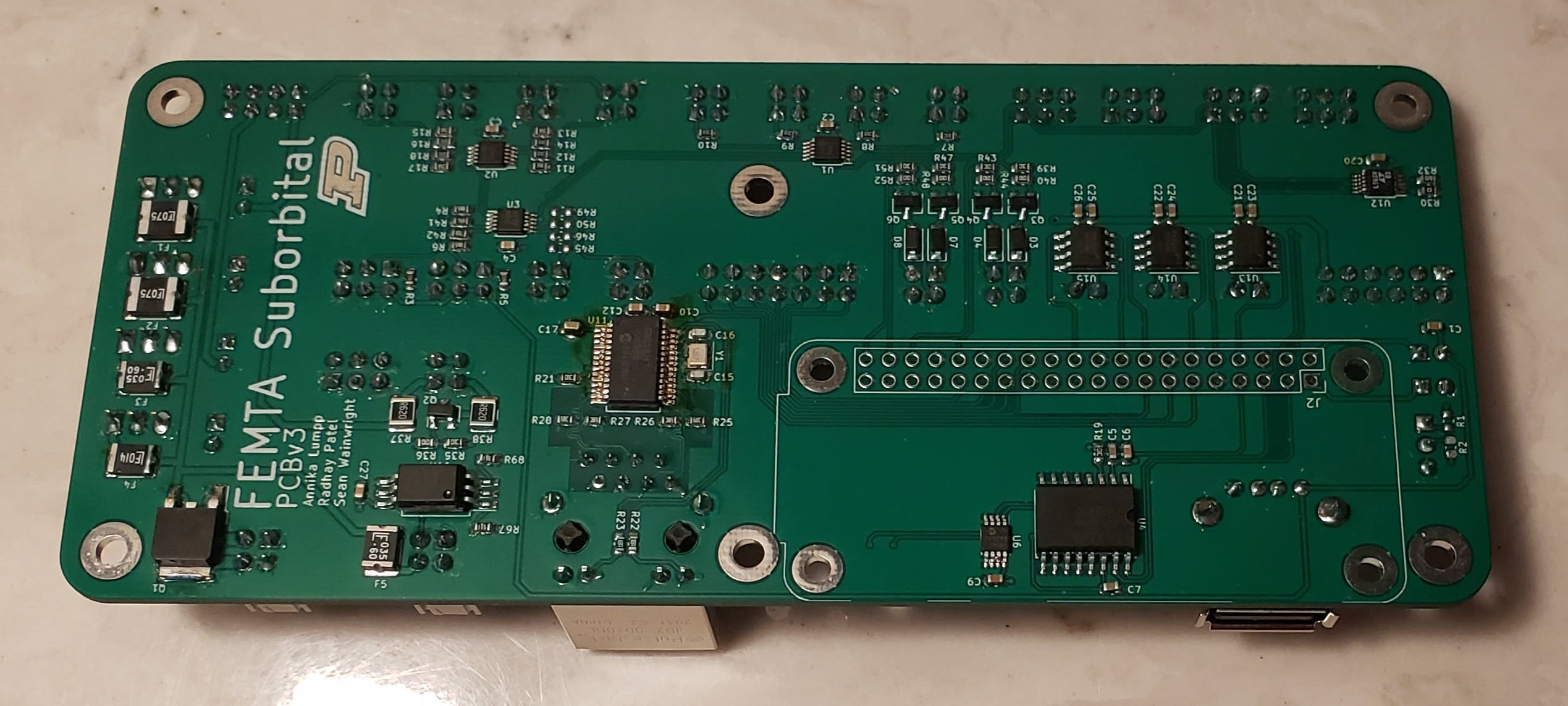 Rectangular green PCB with various surface-mount components, 'FEMTA Suborbital' screenprinted on it